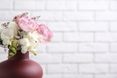 Photo of Beautiful bouquet with roses against white brick wall, closeup. Space for text
