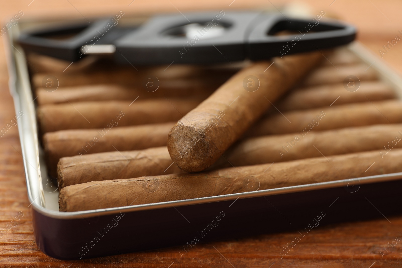 Photo of Cigars in box on wooden table, closeup