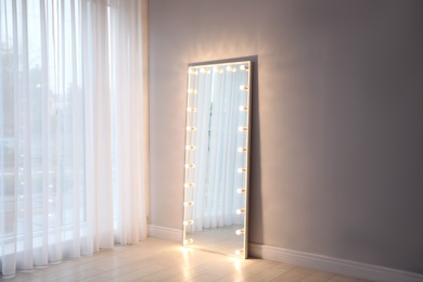 Image of Full length dressing mirror with lamps in stylish room interior