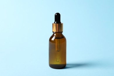 Photo of Bottle of cosmetic oil on light blue background