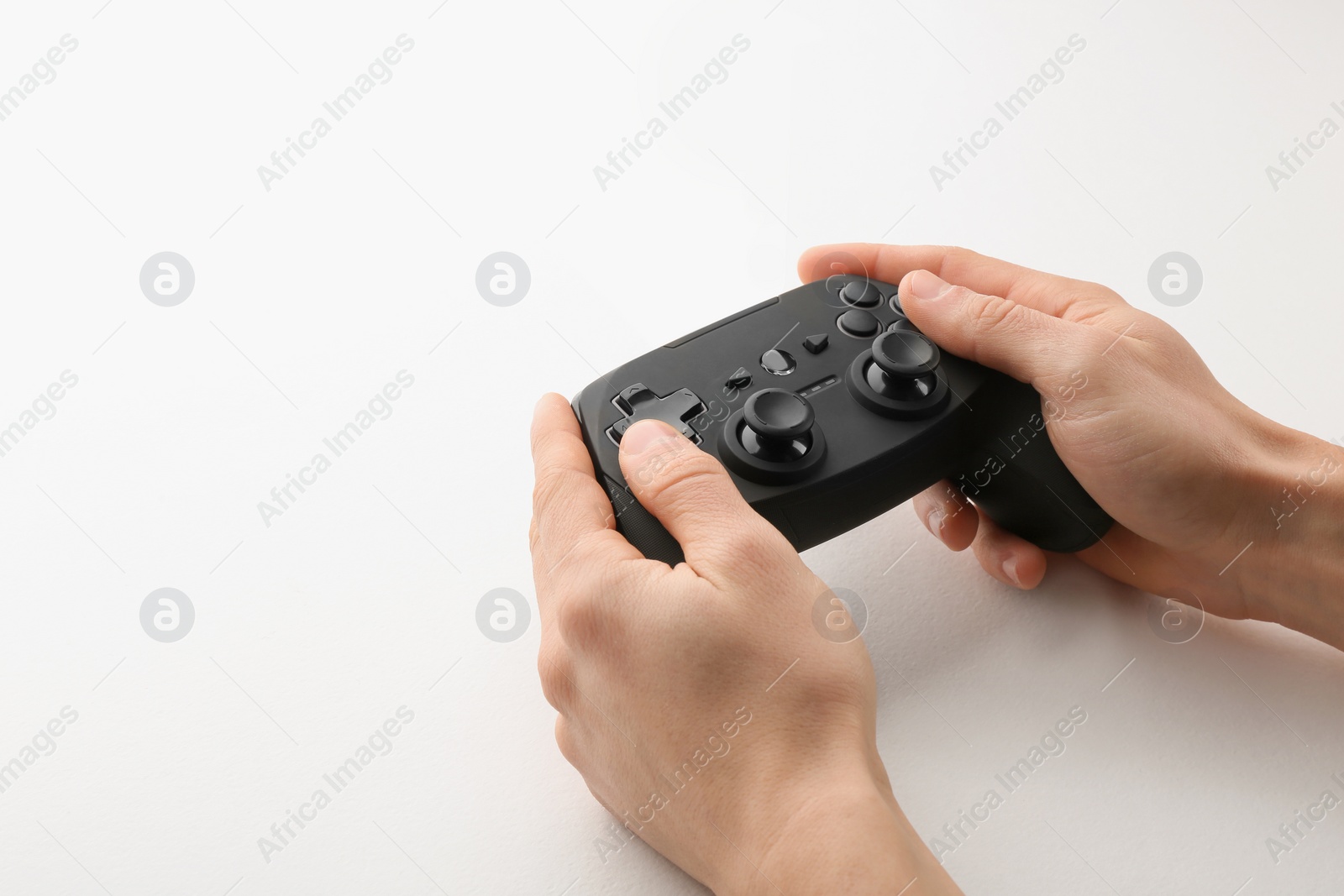 Photo of Young man holding video game controller on white background, closeup