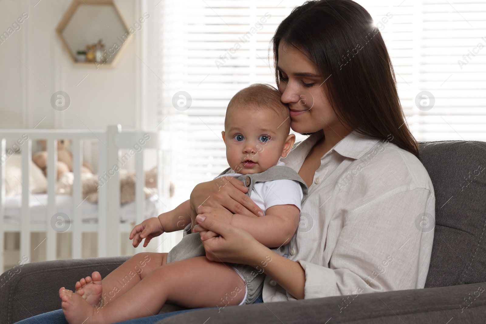 Photo of Happy young mother with her baby in armchair at home