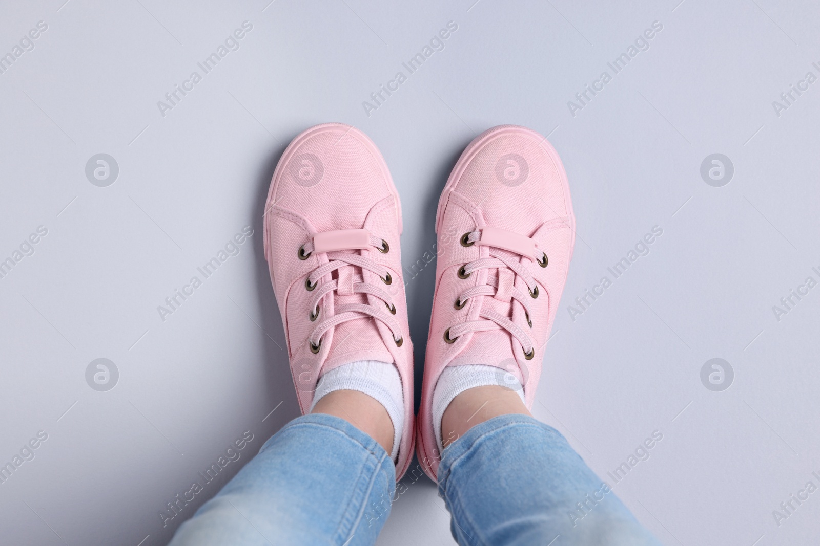 Photo of Woman in stylish sneakers standing on light background, top view