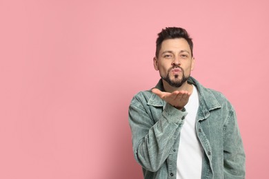 Photo of Handsome man blowing kiss on pink background. Space for text