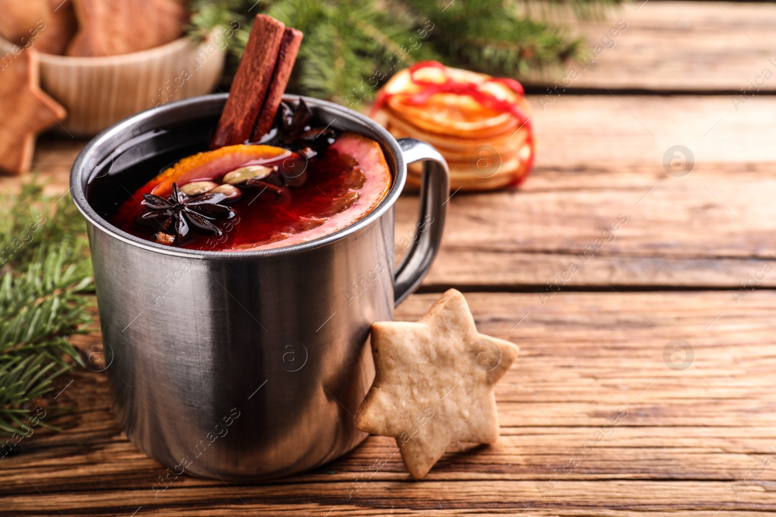 Photo of Aromatic mulled wine and cookie on wooden table, closeup. Space for text