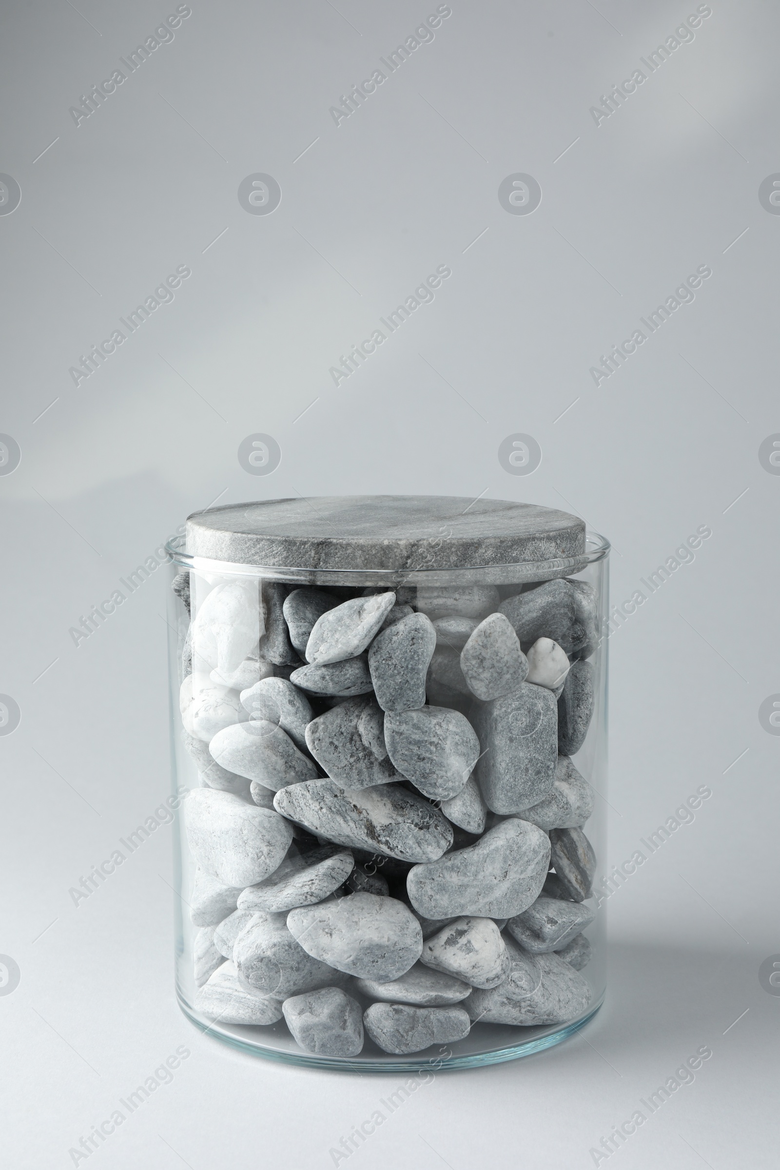 Photo of Presentation for product. Glass container with stones on light grey background. Space for text