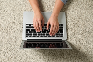 Young woman using laptop for search on floor, top view