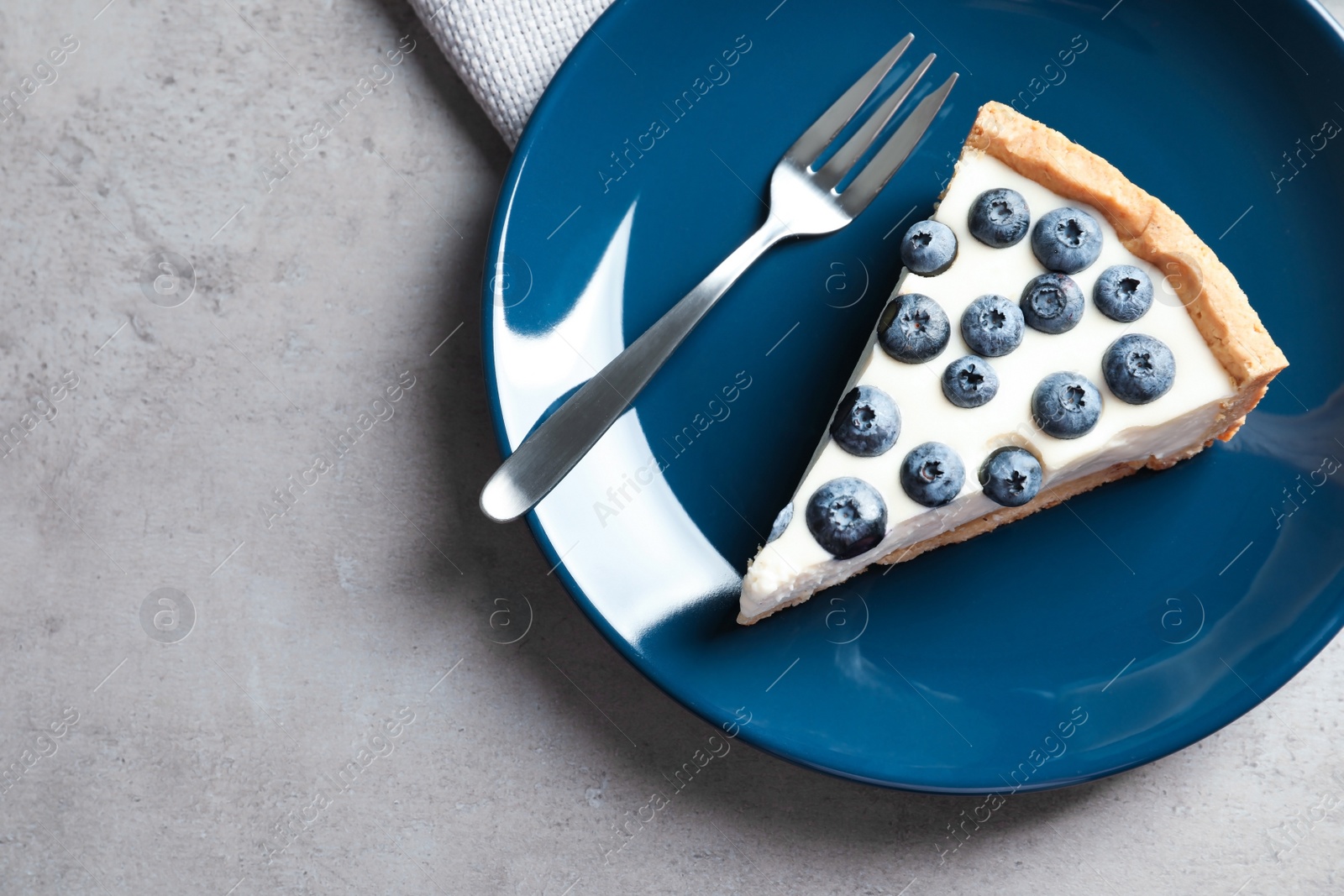 Photo of Piece of tasty blueberry cake and space for text on gray table, top view