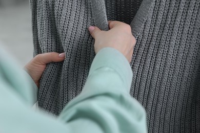 Photo of Woman touching clothes made of soft knitted fabric, closeup