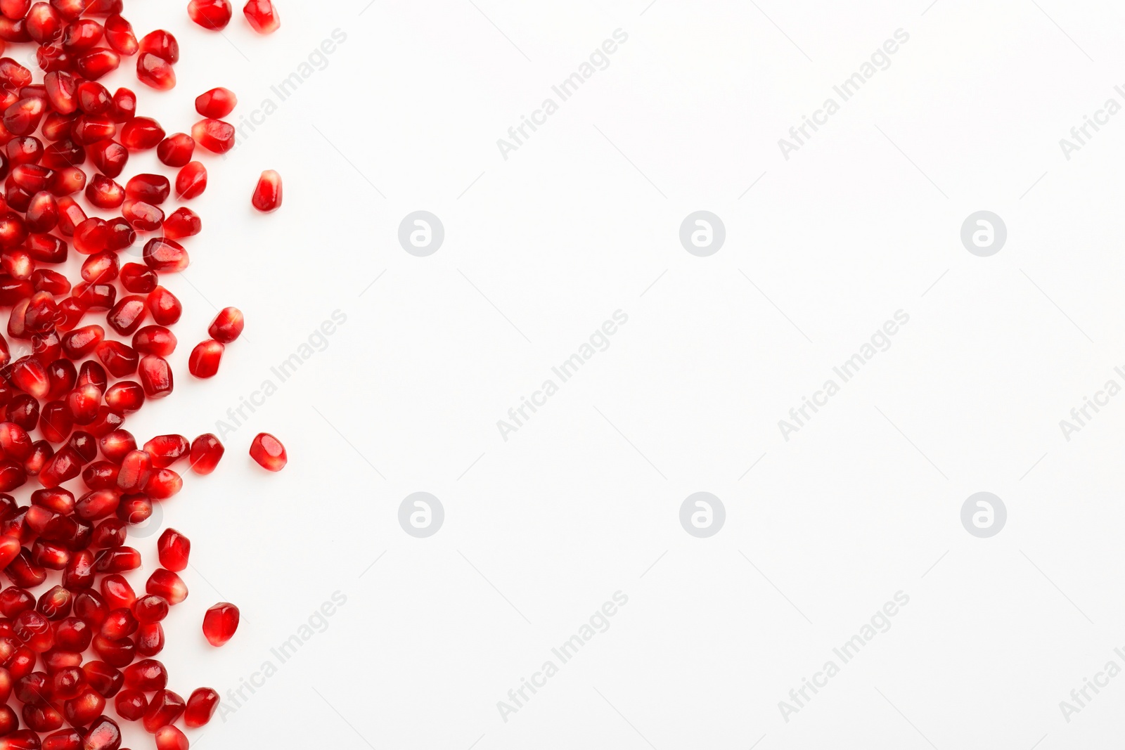 Photo of Many ripe juicy pomegranate grains on white background, flat lay. Space for text