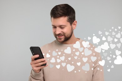 Long distance love. Man chatting with sweetheart via smartphone on grey background. Hearts flying out of device