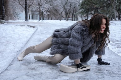 Photo of Young woman fallen on slippery icy pavement in park