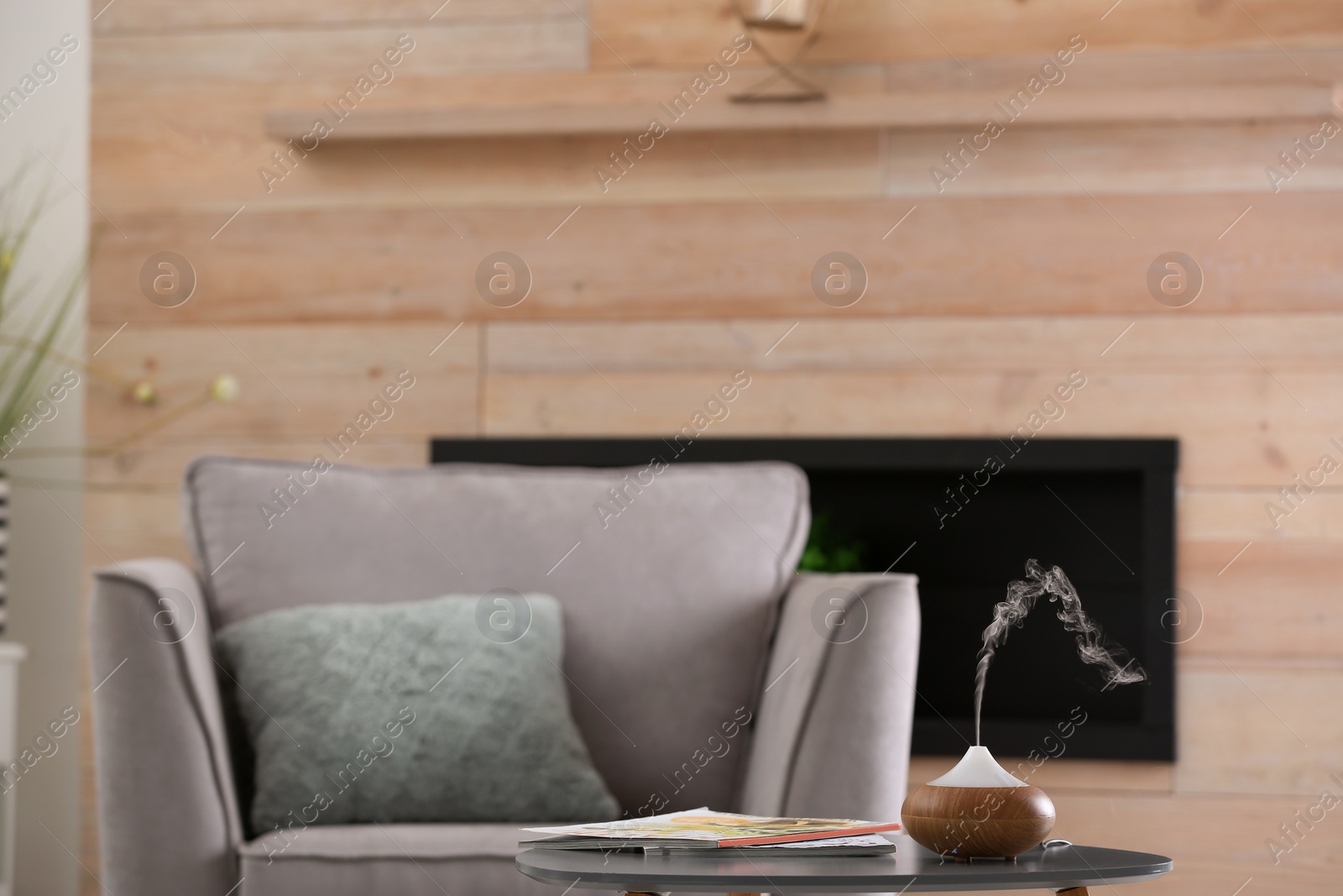 Photo of Stylish room interior with aroma oil diffuser lamp on table