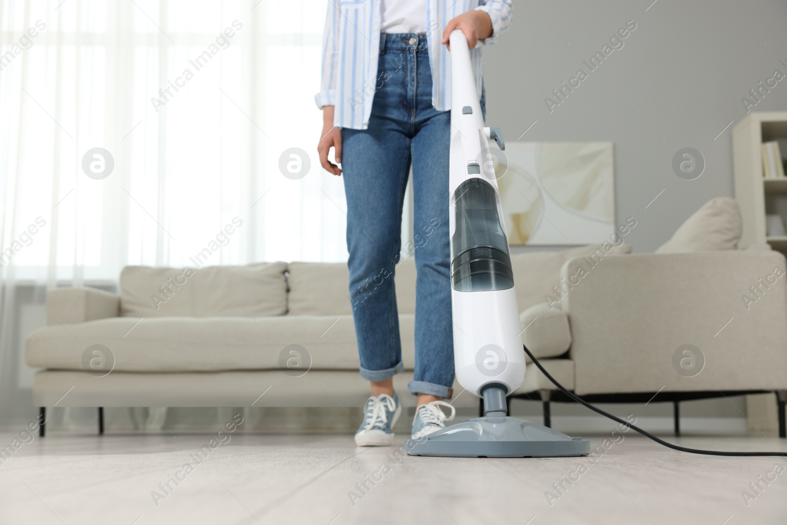 Photo of Woman cleaning floor with steam mop at home, closeup