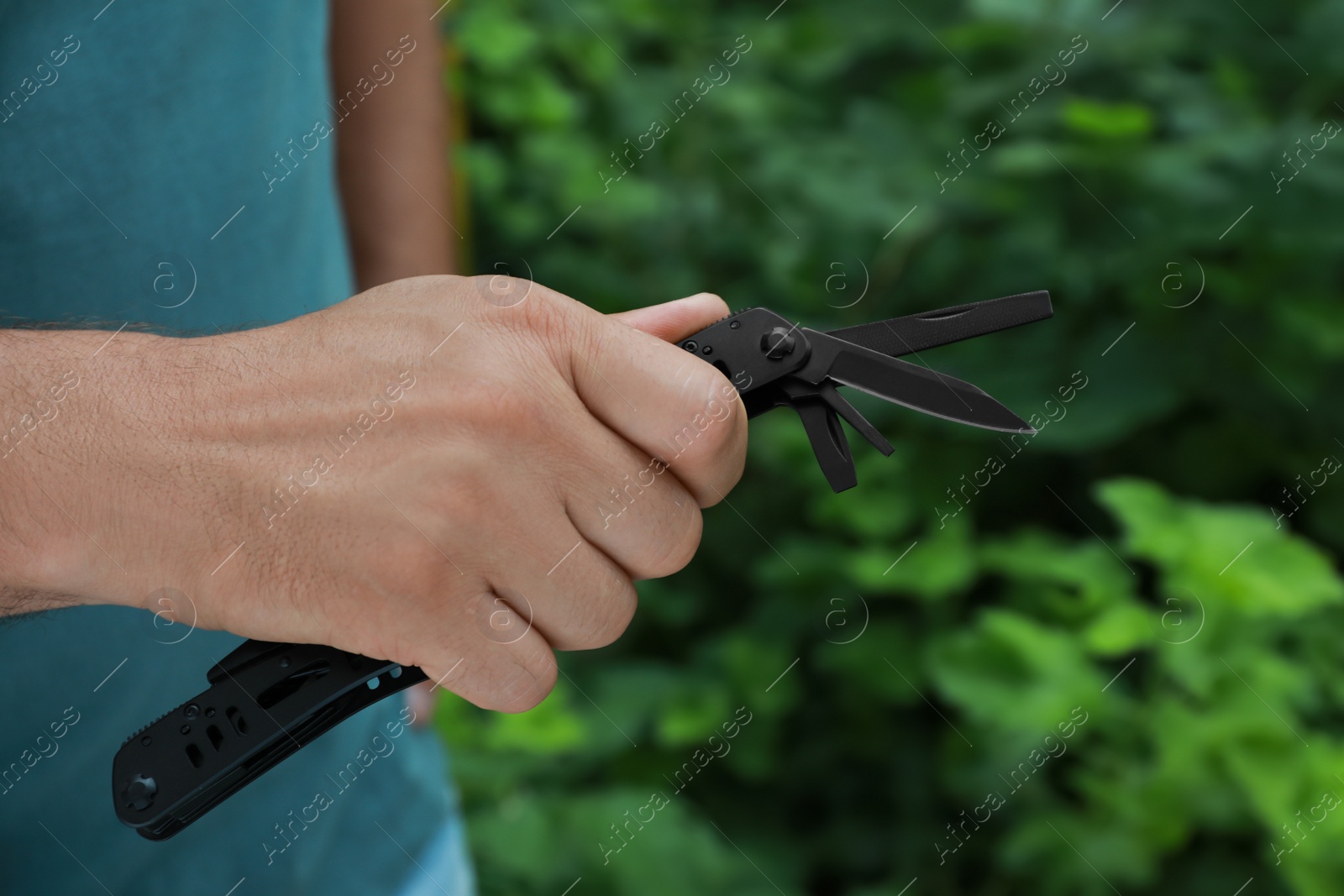 Photo of Man holding compact portable multitool outdoors, closeup