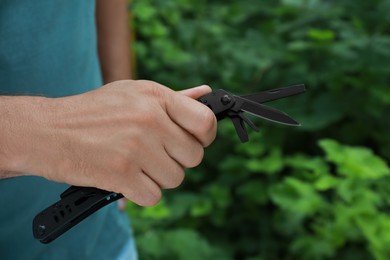 Man holding compact portable multitool outdoors, closeup