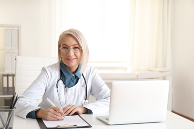 Portrait of mature female doctor in white coat at workplace