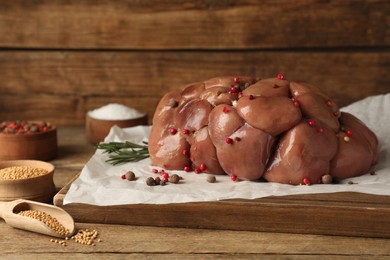 Photo of Fresh raw kidney meat with spices and rosemary on wooden table