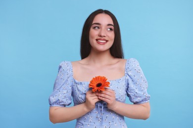 Beautiful woman with spring flower in hands on light blue background