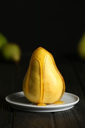 Pouring sweet syrup onto fresh ripe pear on table against blurred background