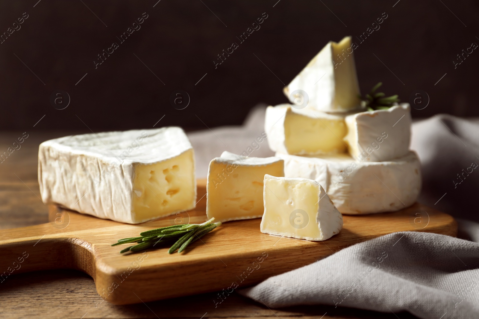 Photo of Wooden board with delicious cheeses on table