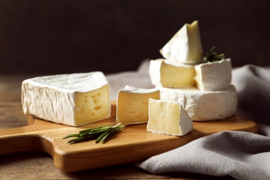 Photo of Wooden board with delicious cheeses on table