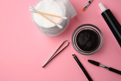 Flat lay composition with eyebrow henna and tools on pink background. Space for text