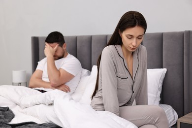 Photo of Offended couple ignoring each other after quarrel in bedroom, selective focus. Relationship problems