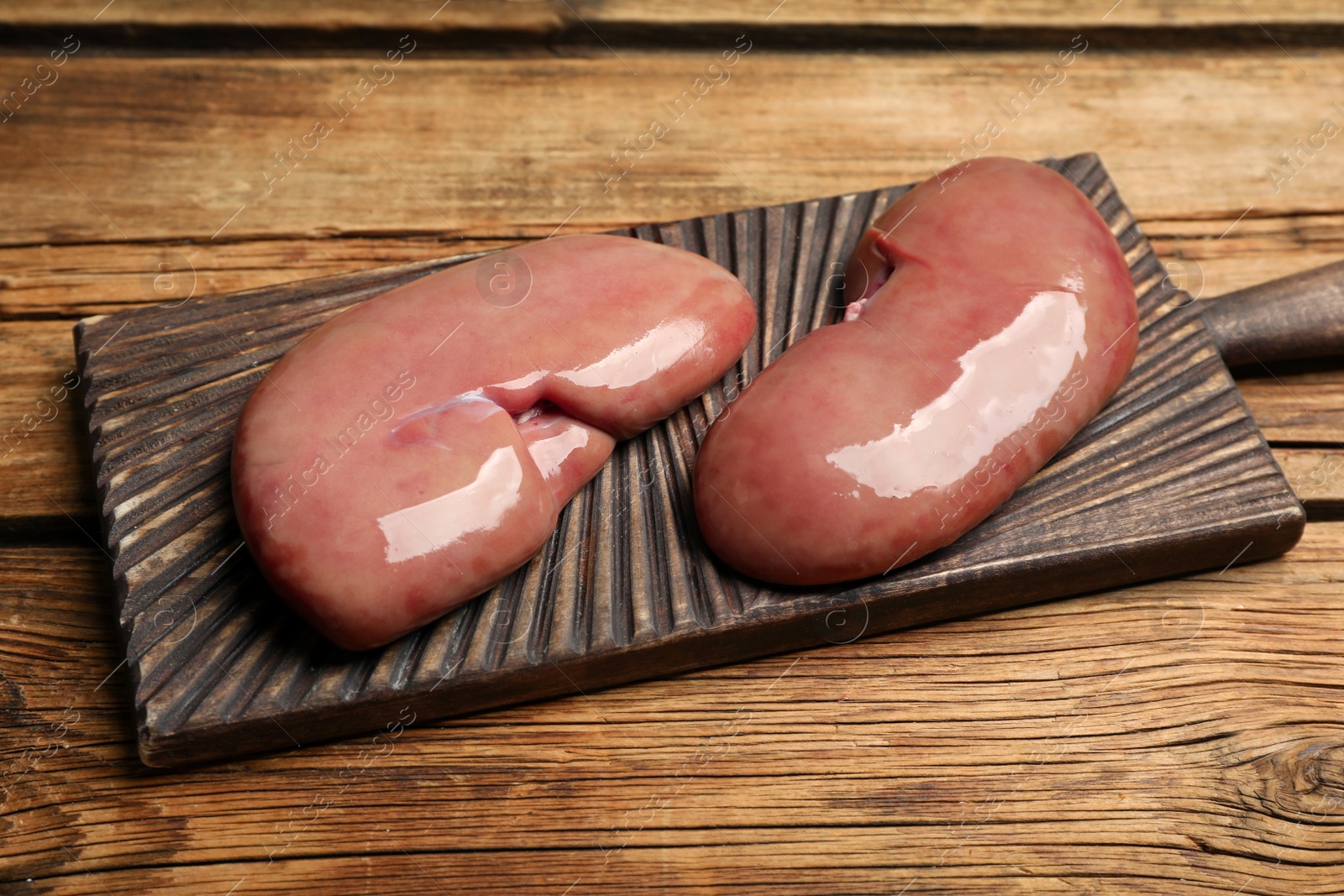 Photo of Fresh raw pork kidneys on wooden table