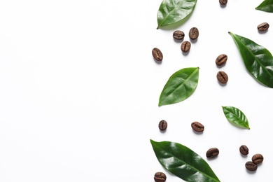 Photo of Fresh green coffee leaves and beans on white background, top view