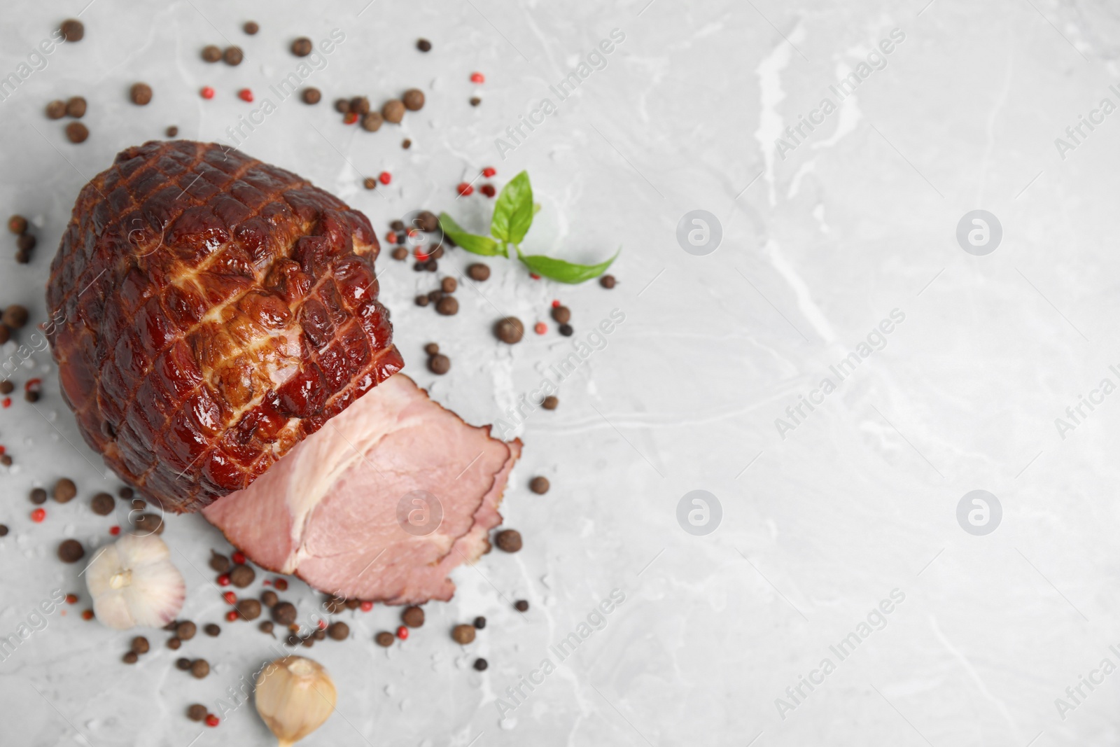 Photo of Delicious ham with spices, garlic and basil on grey marble table, flat lay. Space for text