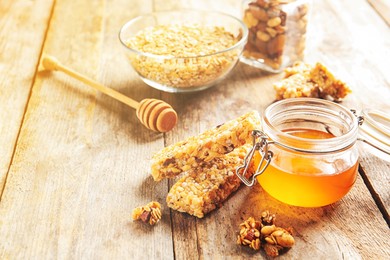 Image of Homemade grain cereal bars and honey on wooden table