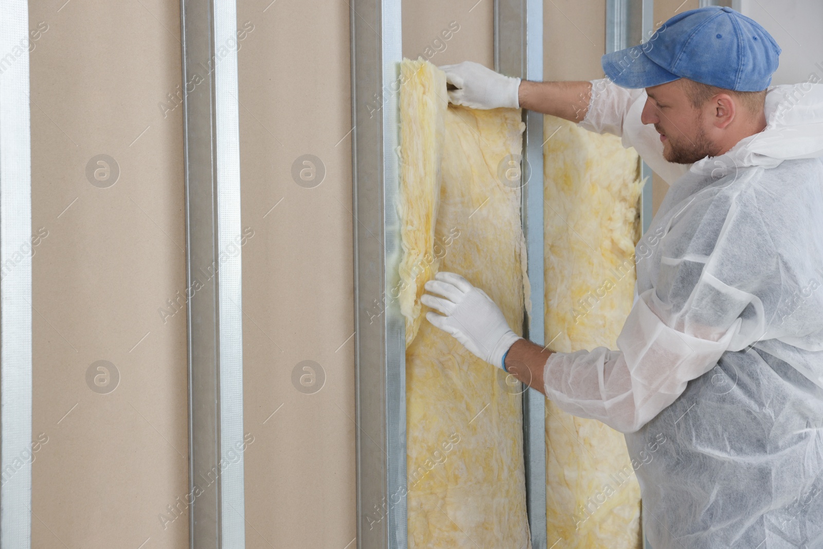 Photo of Worker insulating wall indoors. Space for text