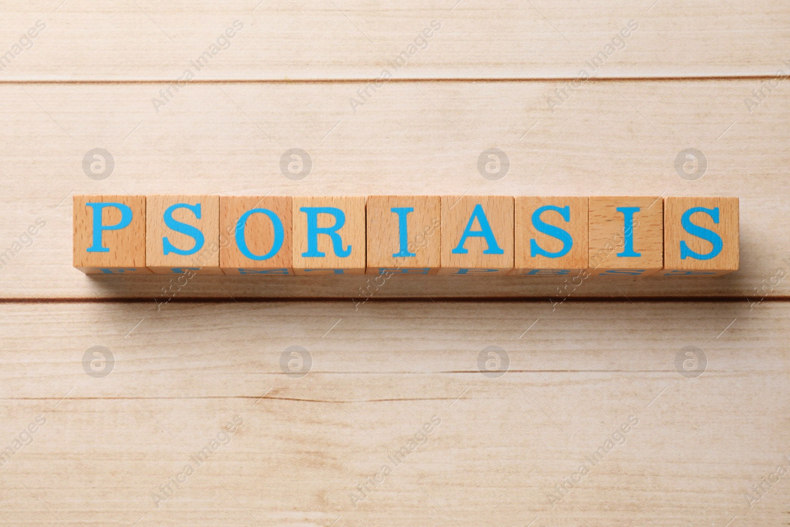 Photo of Word Psoriasis made of cubes with letters on white wooden table, top view