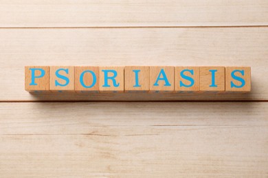 Word Psoriasis made of cubes with letters on white wooden table, top view