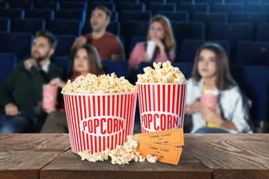 Image of Popcorn, tickets on table and young people in cinema hall