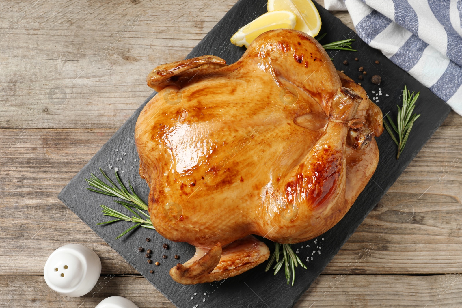 Photo of Tasty roasted chicken with spices and lemon on wooden table, top view