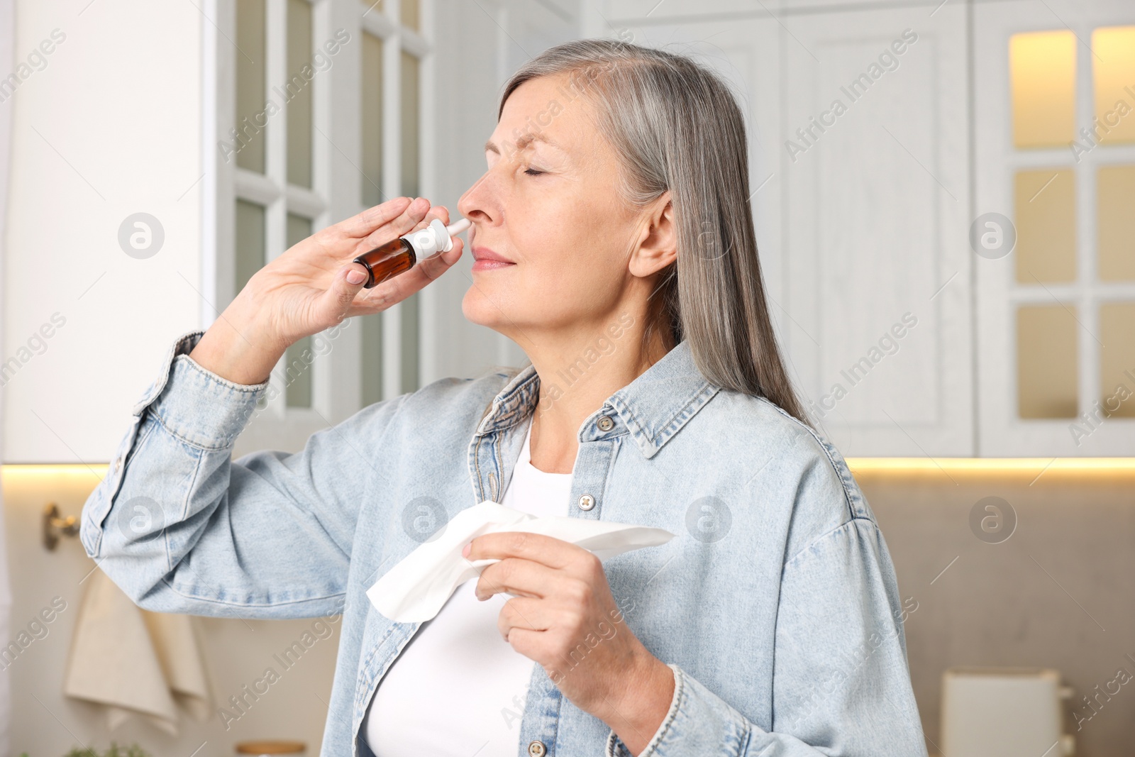 Photo of Medical drops. Woman with tissue using nasal spray indoors