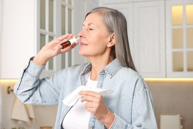 Photo of Medical drops. Woman with tissue using nasal spray indoors