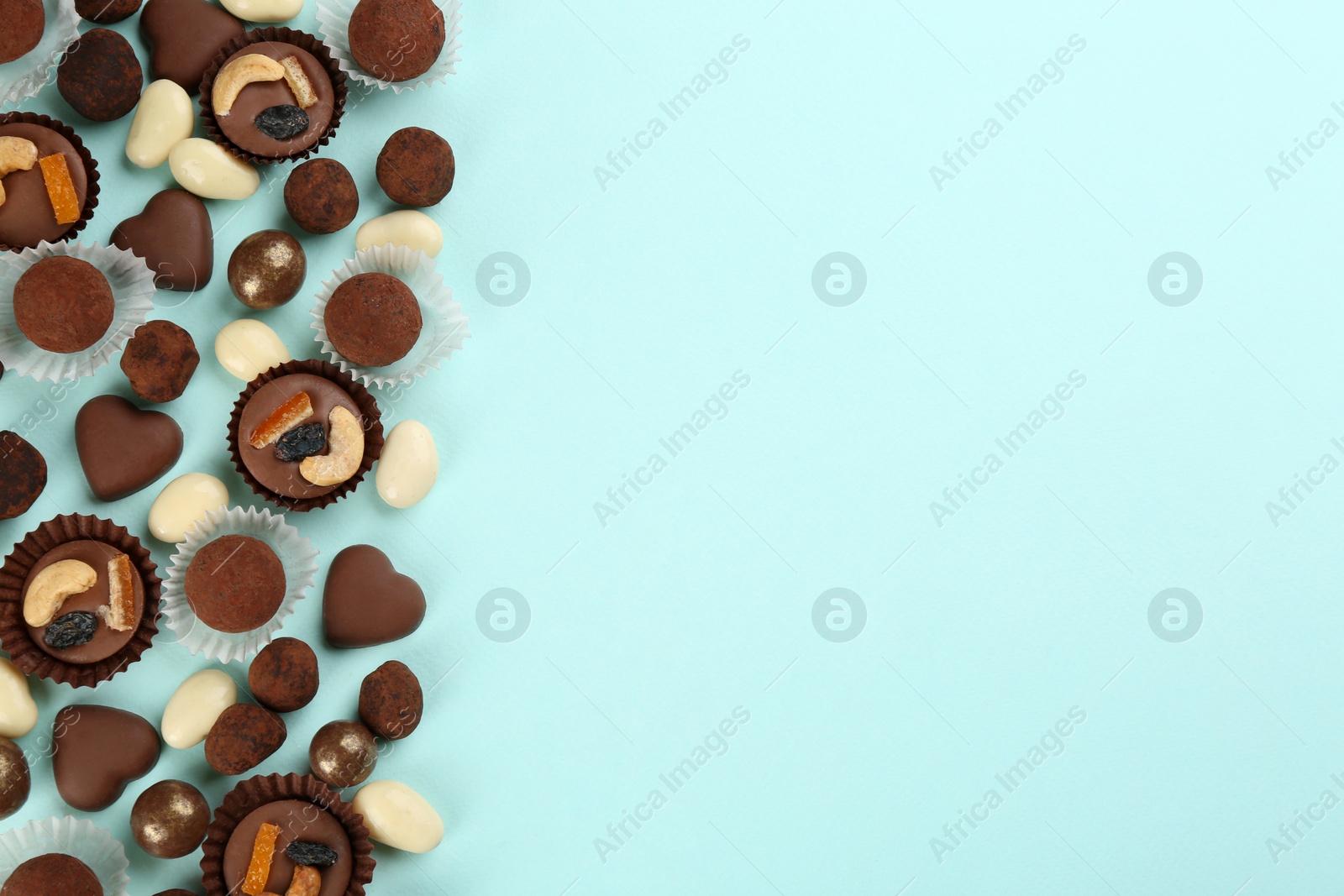 Photo of Different delicious chocolate candies on light blue background, flat lay. Space for text