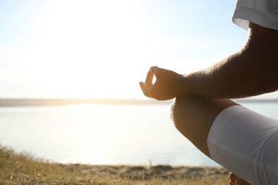 Man near river at sunset, closeup view with space for text. Nature healing power