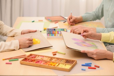 Photo of Artists drawing with soft pastels and pencils at table, closeup