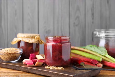 Photo of Tasty rhubarb sauce and ingredients on wooden table, space for text