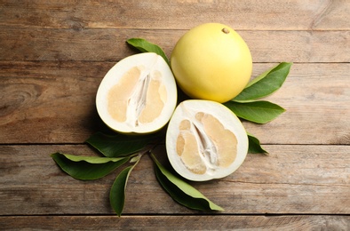 Photo of Fresh cut and whole pomelo fruits on wooden table, flat lay