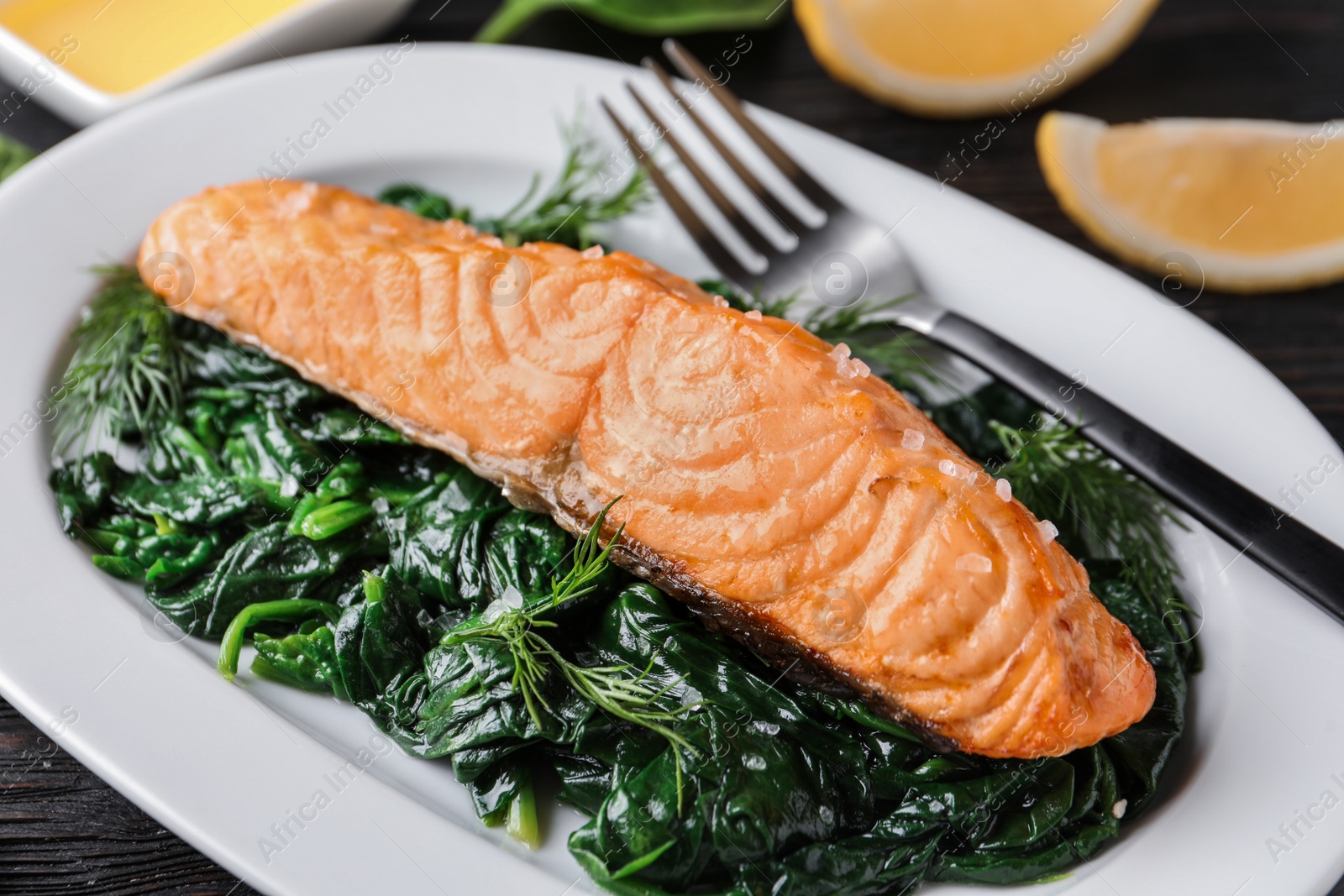 Photo of Tasty salmon with spinach on plate, closeup