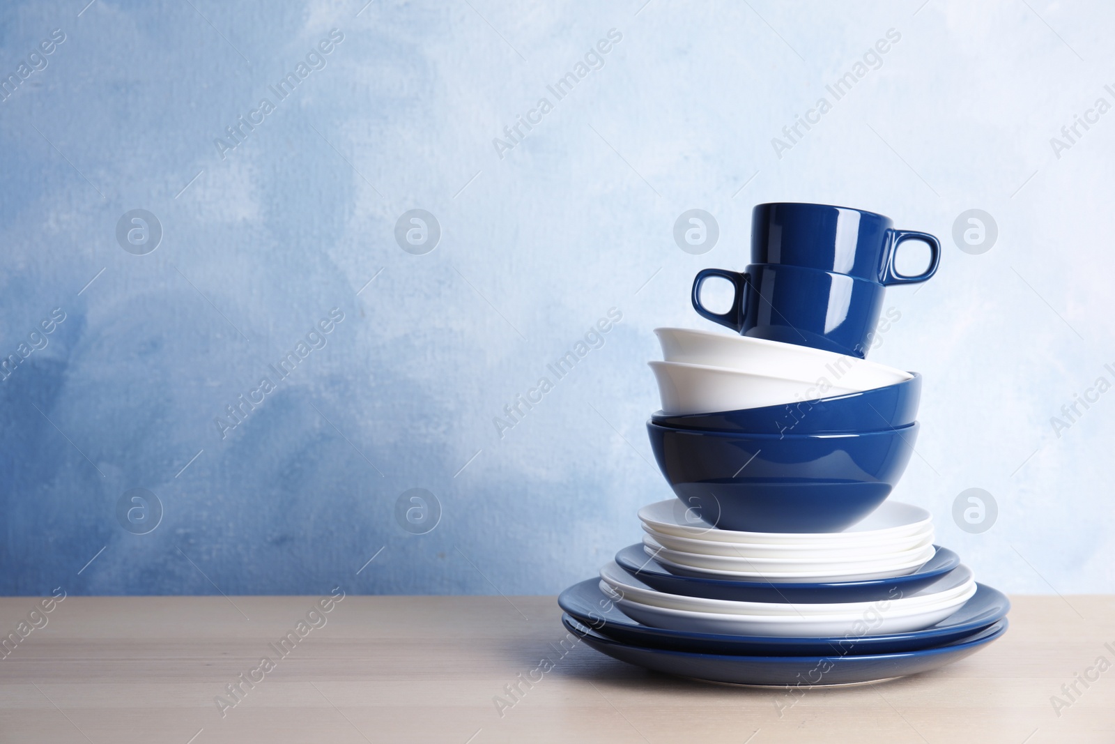 Photo of Set of dinnerware on table against color background with space for text. Interior element