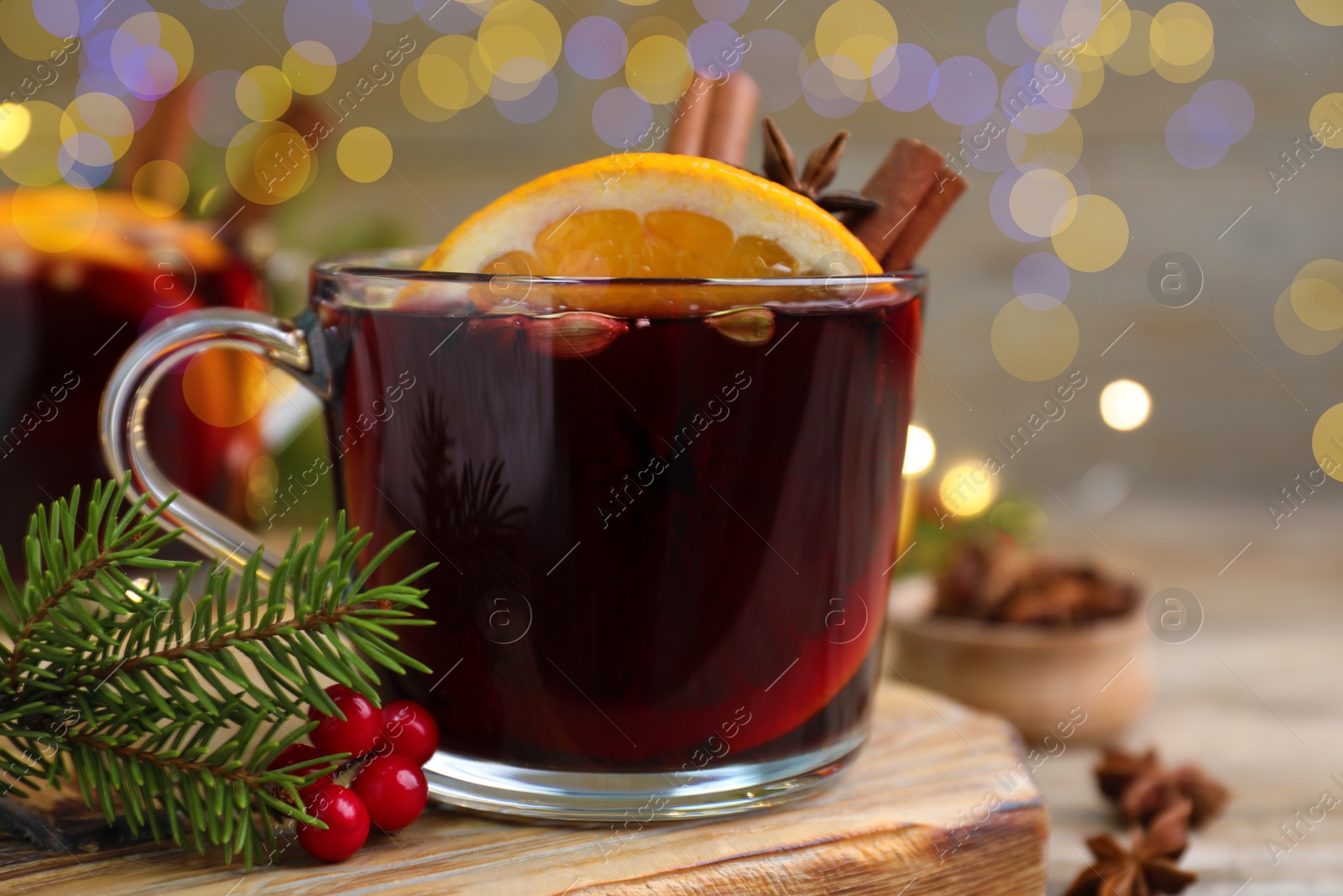 Photo of Aromatic mulled wine on wooden board, closeup