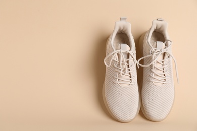 Pair of stylish sport shoes on beige background, top view. Space for text