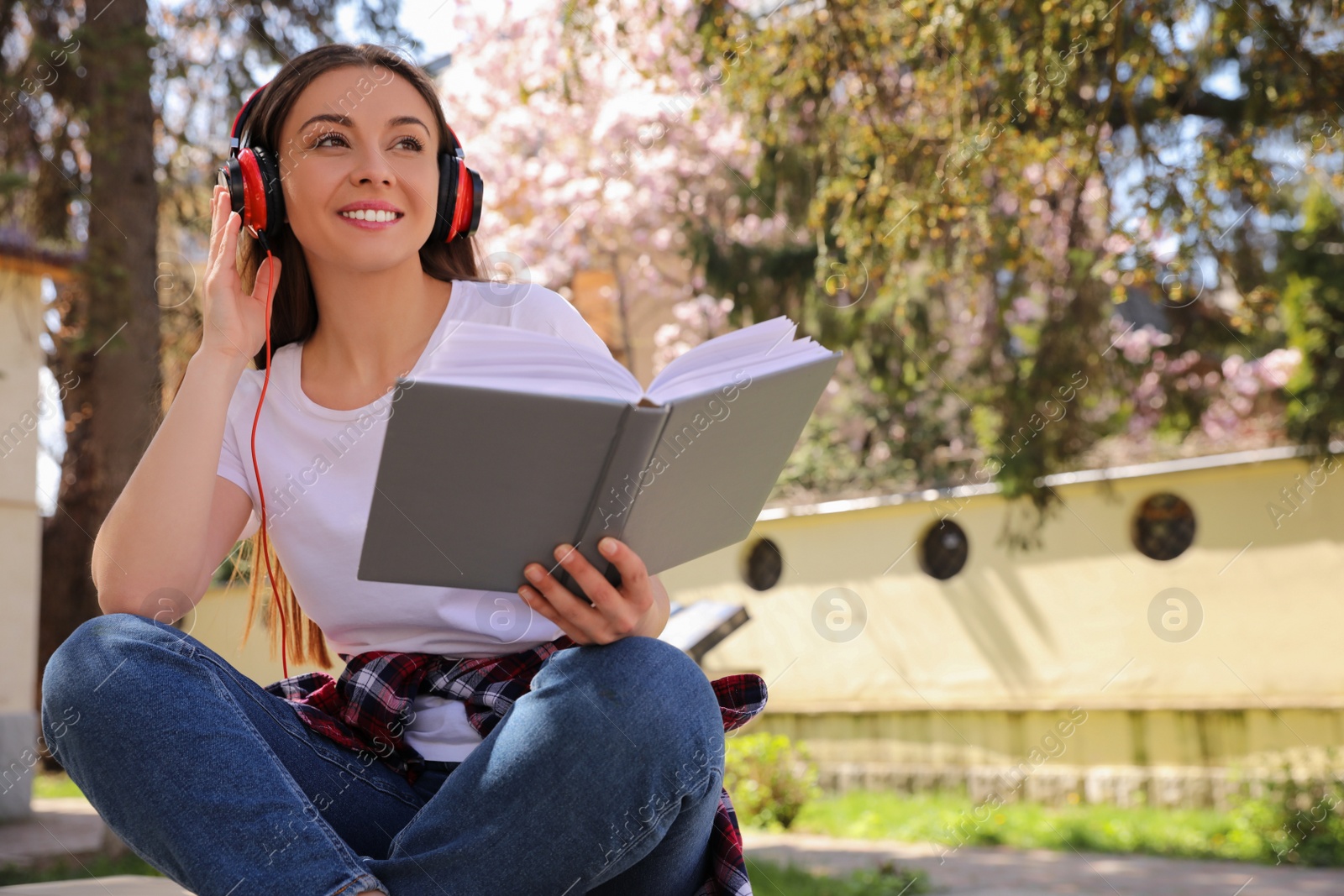 Photo of Happy young woman reading book in park