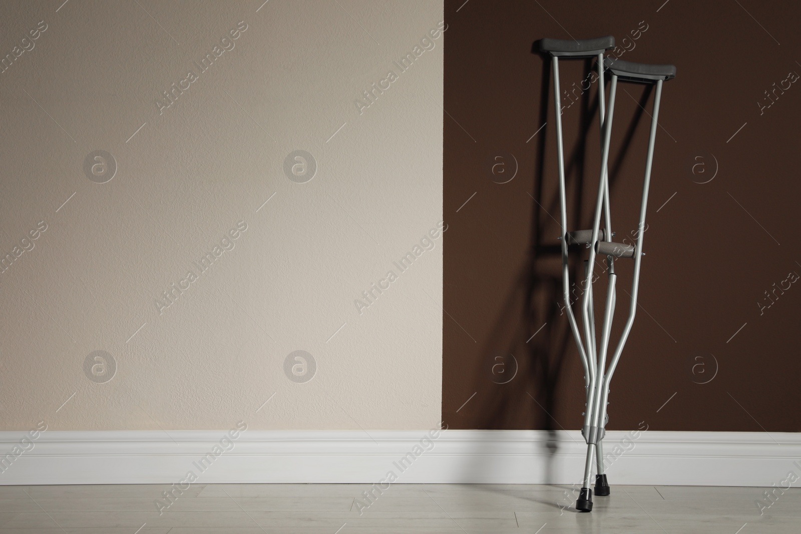 Photo of Pair of axillary crutches near color wall. Space for text